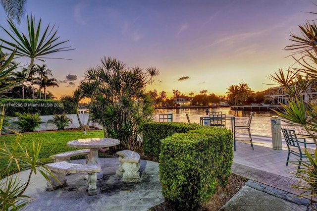 patio terrace at dusk featuring a water view