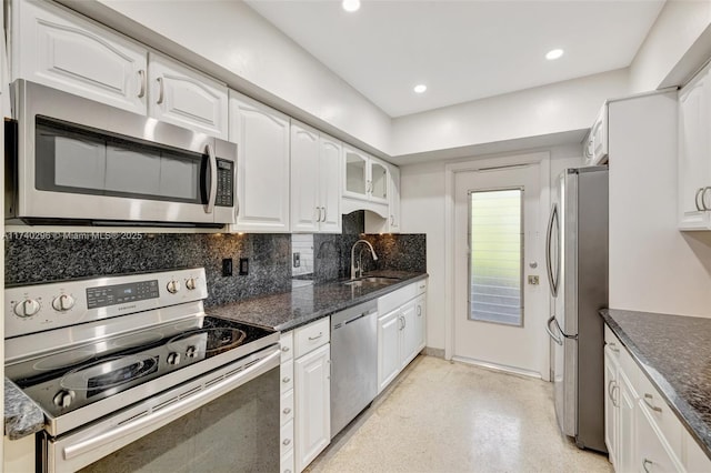 kitchen featuring sink, appliances with stainless steel finishes, backsplash, white cabinets, and dark stone counters