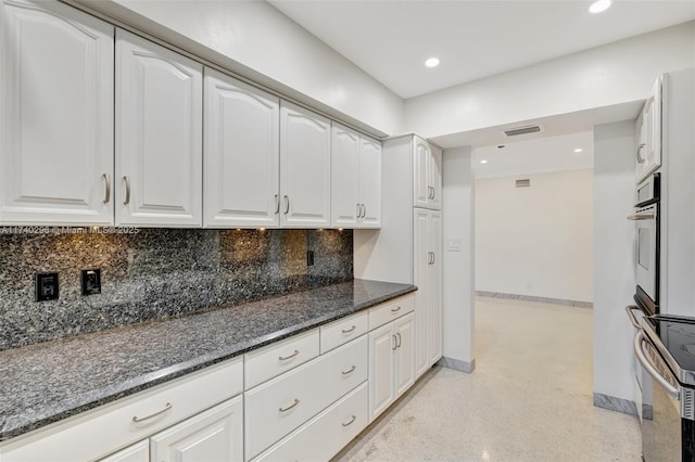 kitchen with white cabinetry, dark stone counters, and tasteful backsplash