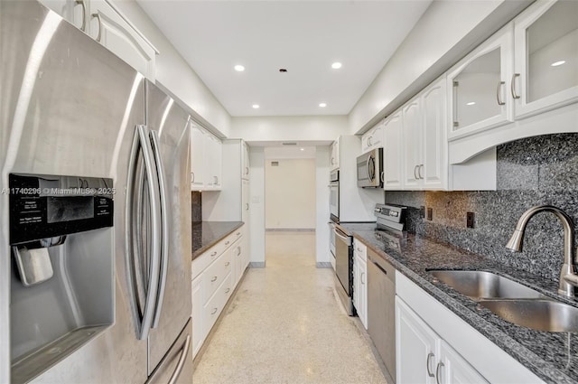 kitchen featuring sink, white cabinetry, dark stone countertops, appliances with stainless steel finishes, and backsplash