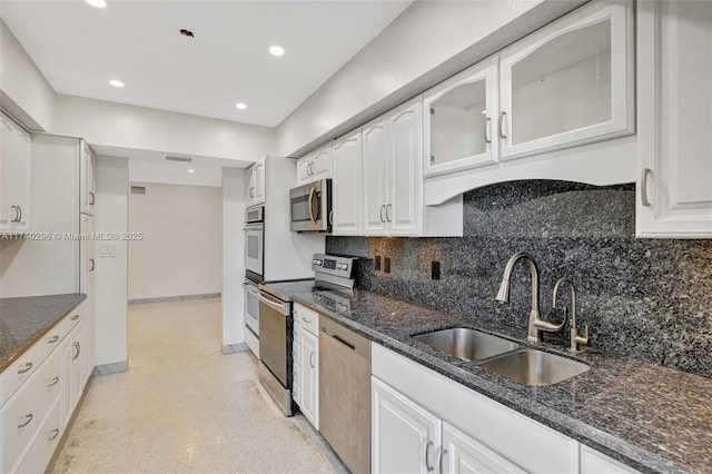 kitchen featuring sink, white cabinetry, appliances with stainless steel finishes, dark stone counters, and decorative backsplash