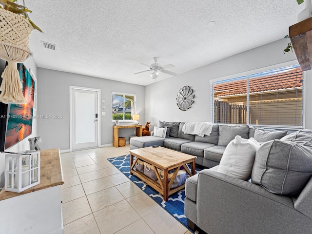 living area featuring visible vents, a ceiling fan, light tile patterned flooring, and a textured ceiling
