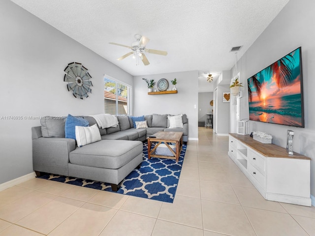 living area featuring light tile patterned floors, a textured ceiling, a ceiling fan, visible vents, and baseboards
