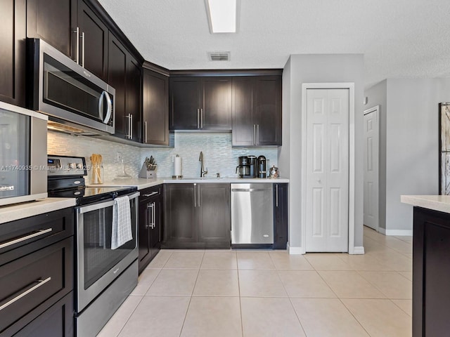 kitchen featuring tasteful backsplash, appliances with stainless steel finishes, sink, and light tile patterned floors