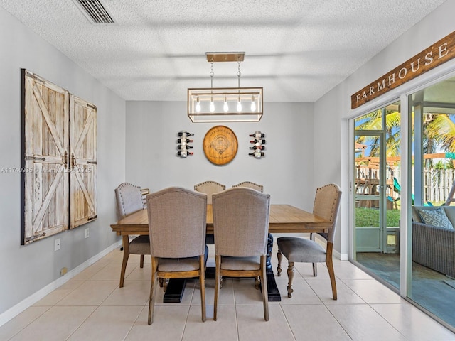 dining room featuring a textured ceiling, light tile patterned floors, baseboards, and visible vents