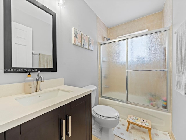 bathroom featuring enclosed tub / shower combo, vanity, and toilet