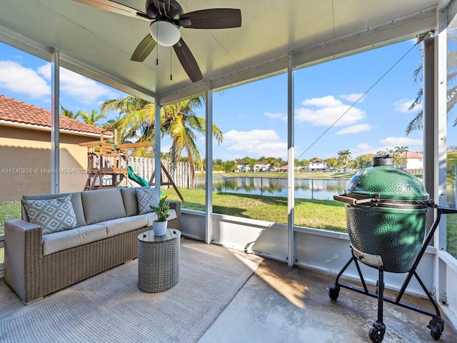 sunroom with ceiling fan and a water view