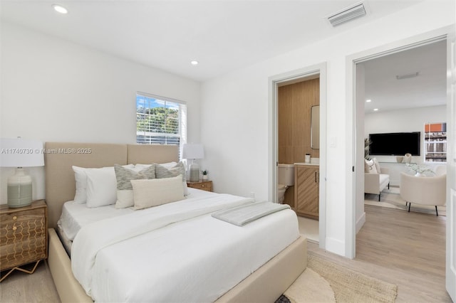 bedroom with ensuite bath and light hardwood / wood-style floors