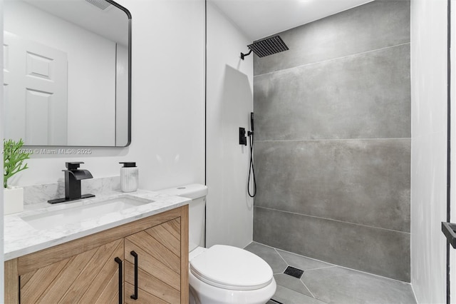 bathroom with tiled shower, vanity, and toilet