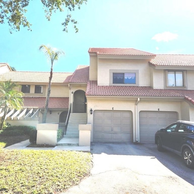 view of front facade with concrete driveway, a tile roof, and stucco siding