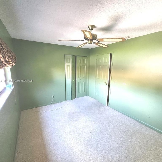 unfurnished bedroom with carpet, a closet, ceiling fan, and a textured ceiling