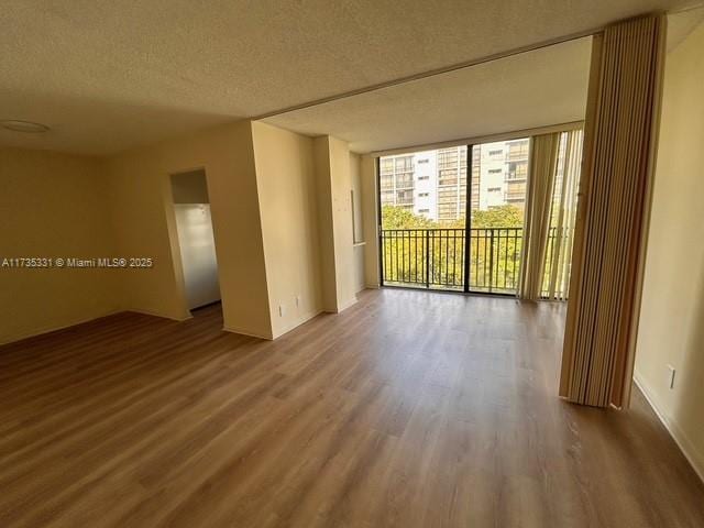 spare room with wood-type flooring, floor to ceiling windows, and a textured ceiling