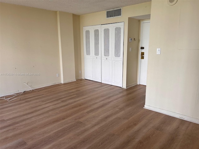 unfurnished bedroom featuring dark hardwood / wood-style flooring, a closet, and a textured ceiling