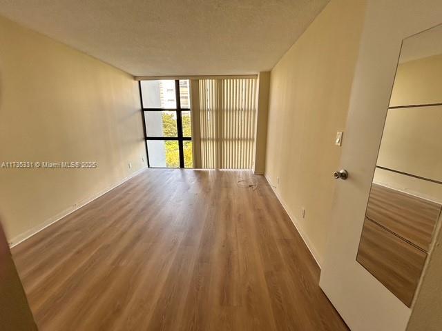 empty room with expansive windows, hardwood / wood-style flooring, and a textured ceiling