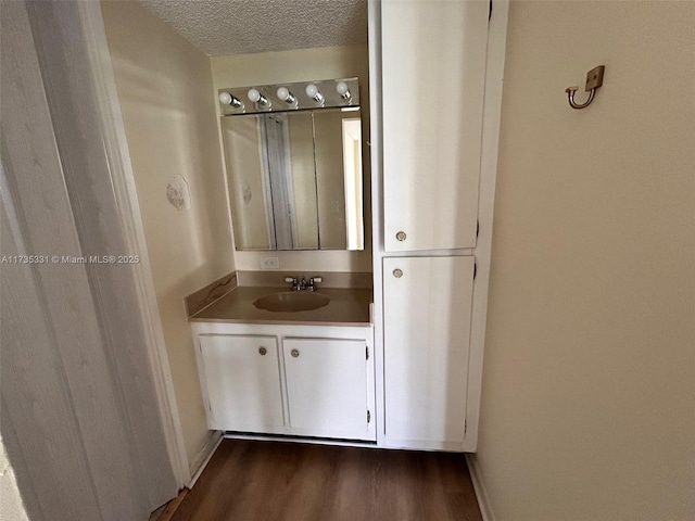 bathroom with hardwood / wood-style flooring, vanity, and a textured ceiling