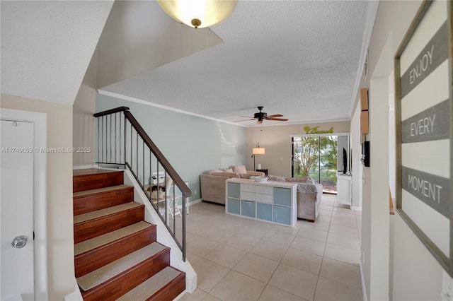 stairs featuring tile patterned flooring, crown molding, ceiling fan, and a textured ceiling