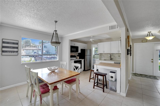 tiled dining room featuring crown molding, plenty of natural light, sink, and a textured ceiling