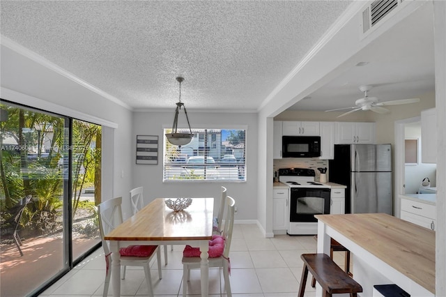 tiled dining area featuring ornamental molding, ceiling fan, and a textured ceiling