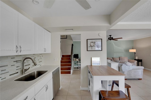 kitchen with sink, light tile patterned floors, ceiling fan, white cabinets, and decorative backsplash