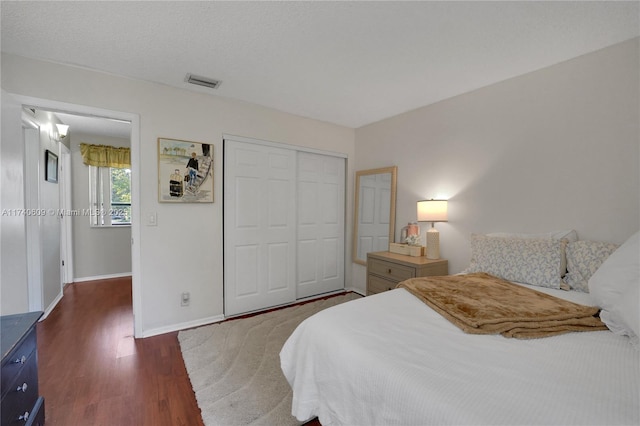 bedroom with dark wood-type flooring, a textured ceiling, and a closet