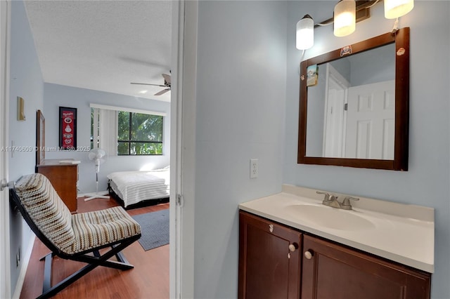 bathroom featuring vanity, ceiling fan, wood-type flooring, and a textured ceiling