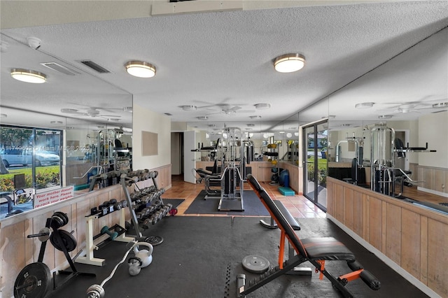 workout area with ceiling fan and a textured ceiling