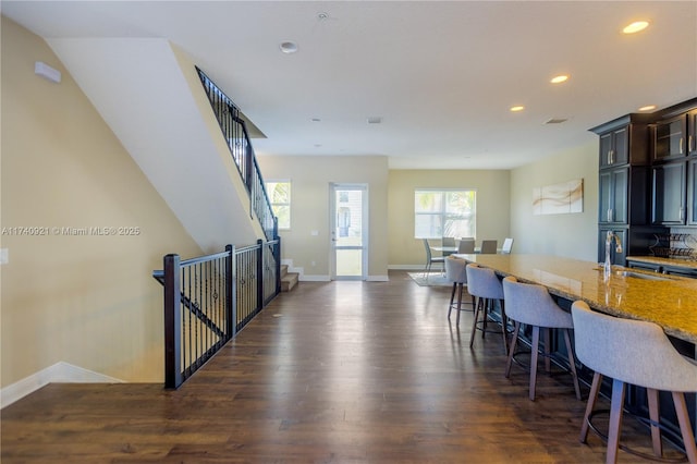 kitchen featuring light stone countertops, sink, a breakfast bar area, and dark wood-type flooring