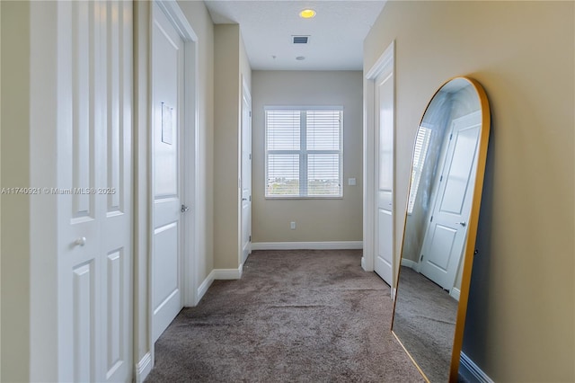 hall with light colored carpet and a textured ceiling