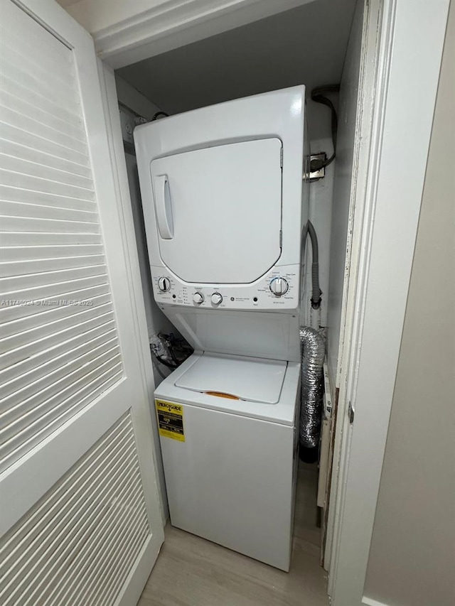 laundry area with stacked washer and dryer and light wood-type flooring