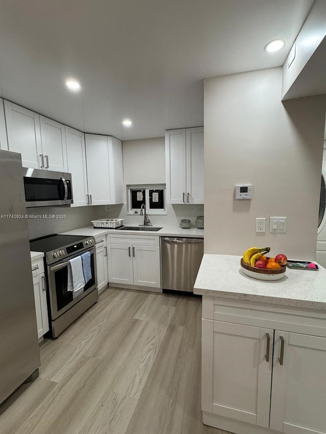 kitchen with sink, light hardwood / wood-style flooring, stainless steel appliances, and white cabinets