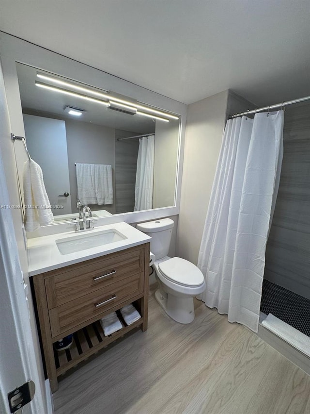 bathroom with vanity, hardwood / wood-style floors, walk in shower, and toilet