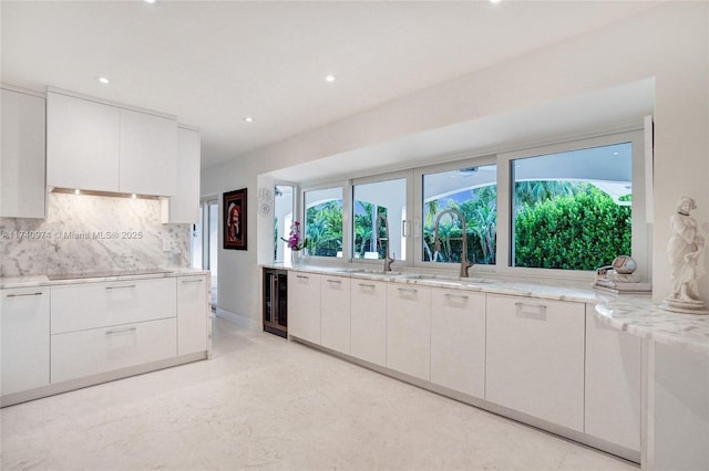 kitchen featuring wine cooler, white cabinetry, and backsplash