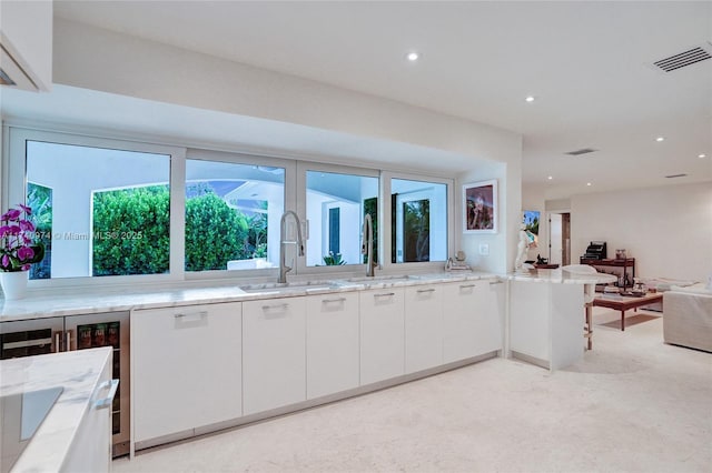 kitchen with open floor plan, white cabinets, a sink, and visible vents