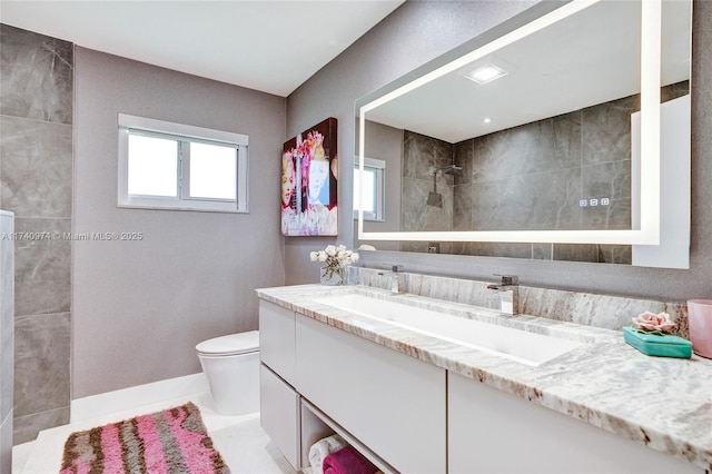 bathroom featuring toilet, baseboards, a walk in shower, and vanity