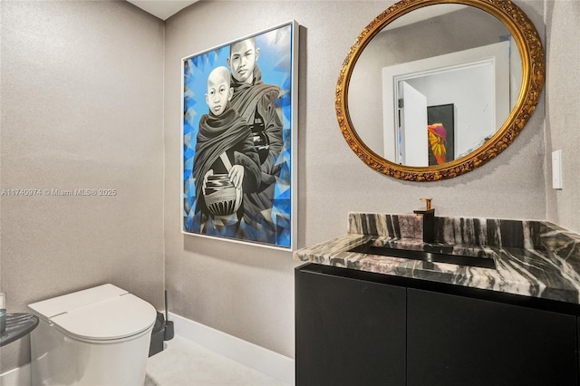 bathroom with toilet, baseboards, and vanity