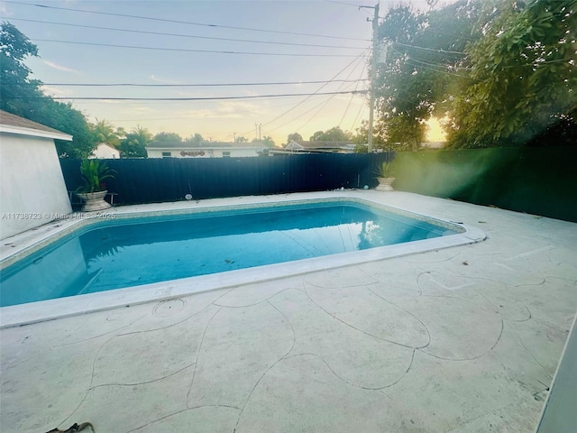 pool at dusk with a patio area