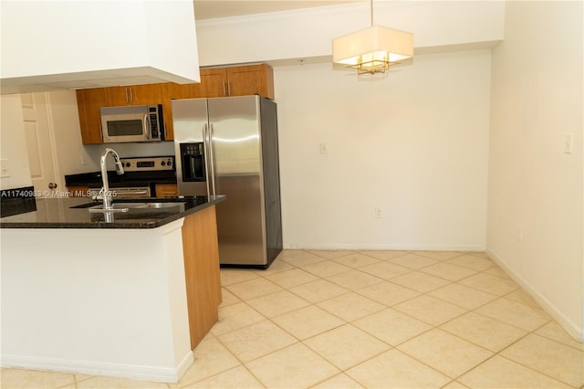 kitchen featuring decorative light fixtures, dark stone countertops, ornamental molding, kitchen peninsula, and stainless steel appliances