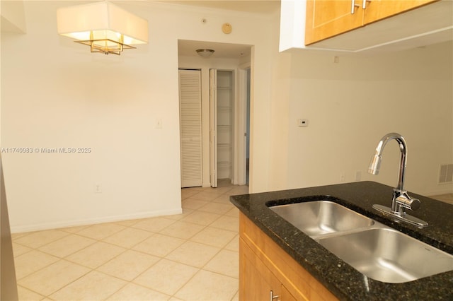 kitchen with crown molding, sink, dark stone countertops, and light tile patterned flooring