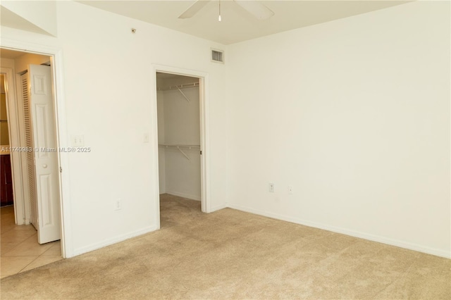 unfurnished bedroom featuring light colored carpet, a spacious closet, and a closet