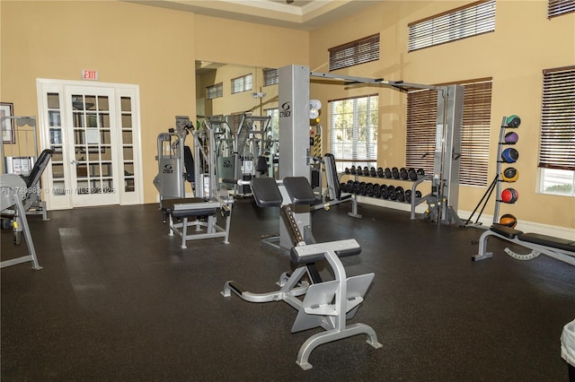 workout area featuring a towering ceiling, a wealth of natural light, and french doors