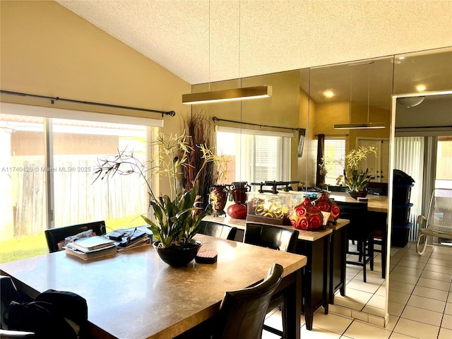 dining space featuring vaulted ceiling, a wealth of natural light, light tile patterned floors, and a textured ceiling