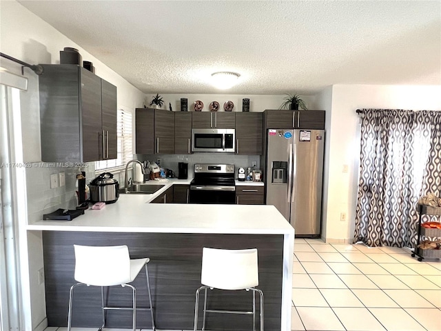 kitchen featuring appliances with stainless steel finishes, sink, a kitchen breakfast bar, and kitchen peninsula