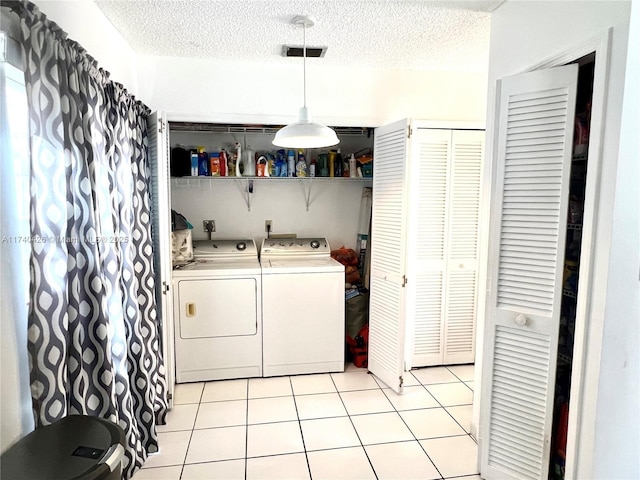 laundry room featuring light tile patterned floors, a textured ceiling, and washing machine and clothes dryer