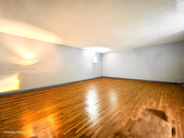 spare room with baseboards and wood finished floors