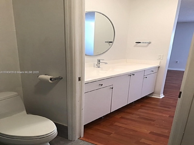 bathroom featuring vanity, wood finished floors, toilet, and baseboards