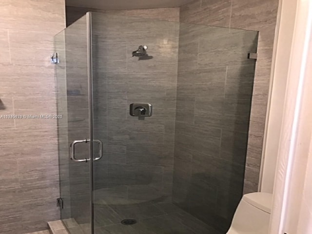 bathroom featuring a stall shower and toilet