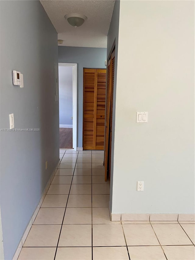 hall featuring light tile patterned floors and a textured ceiling