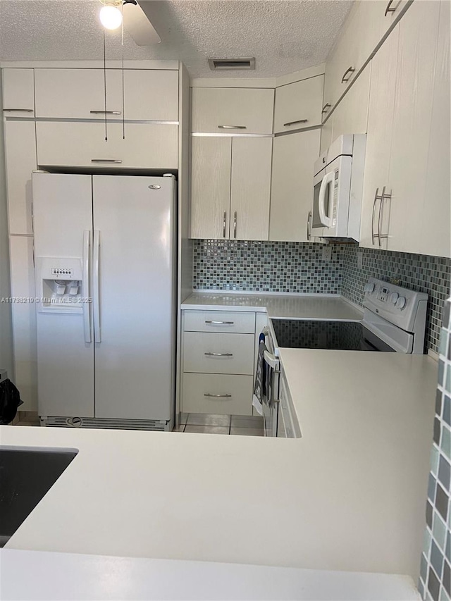 kitchen featuring white appliances, decorative backsplash, and a textured ceiling