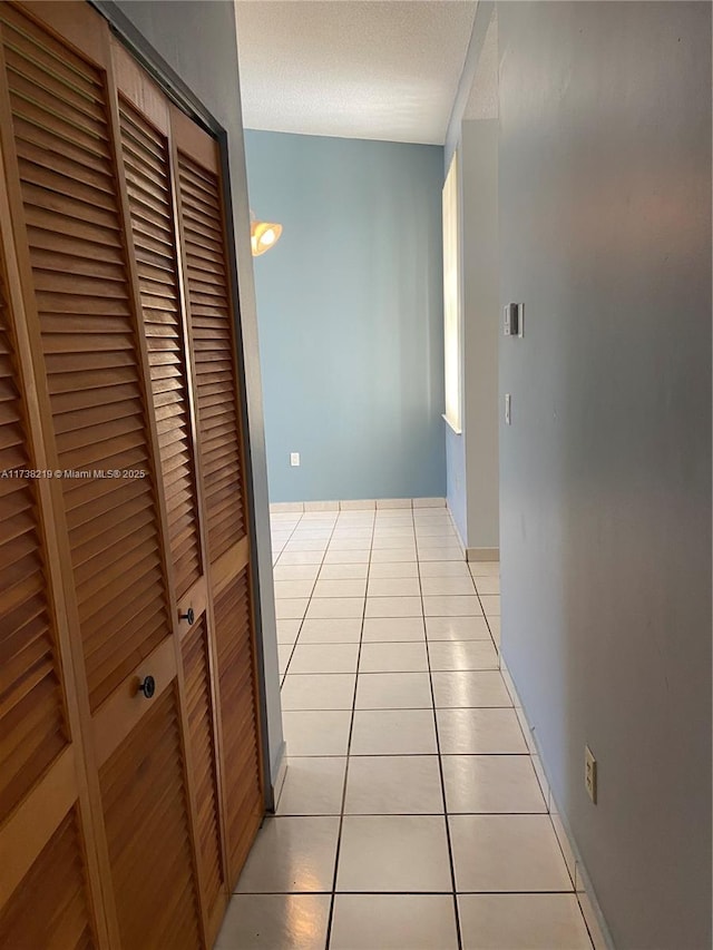 hall with light tile patterned floors and a textured ceiling