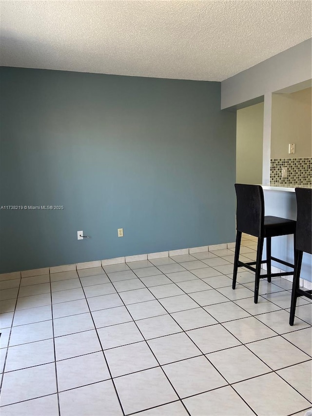 unfurnished room featuring light tile patterned floors and a textured ceiling